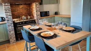 Uma cozinha com parede de tijolos, fogão e mesa de jantar posta com pratos e copos.