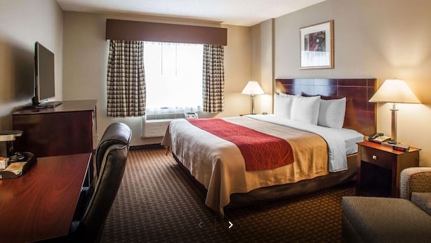 Une chambre d’hôtel équipée d’un lit, d’un bureau, d’une chaise, de lampes et d’un téléviseur.