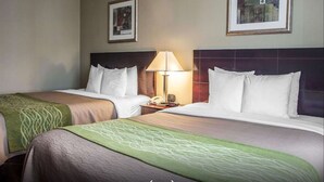 Une chambre d’hôtel avec deux lits, une table de chevet avec une lampe et des œuvres d’art accrochées aux murs.