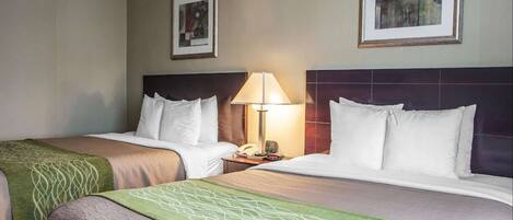 A hotel room with two beds, a nightstand with a lamp, and artwork on the walls.