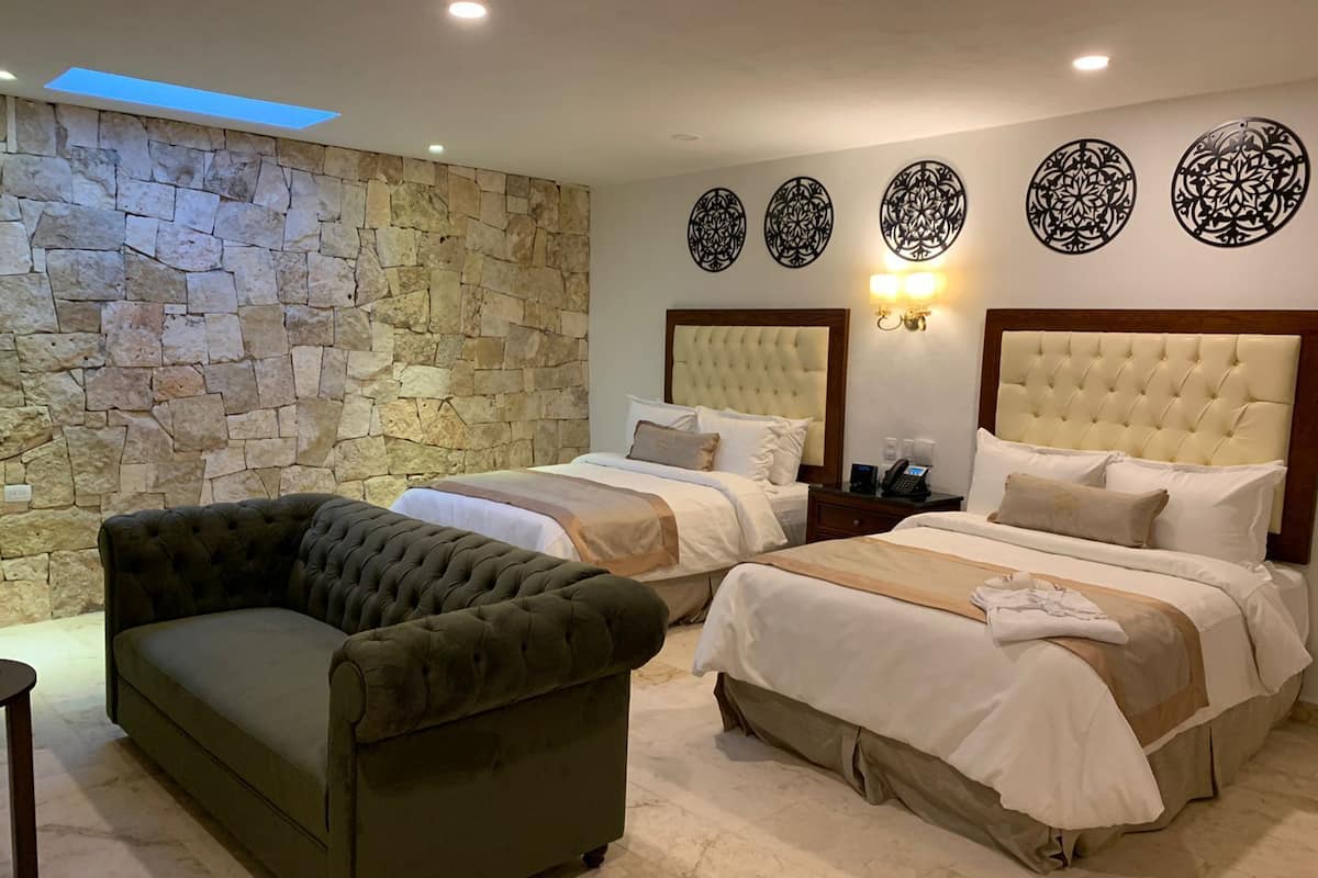 A hotel room with two beds, a stone wall, and decorative wall art.