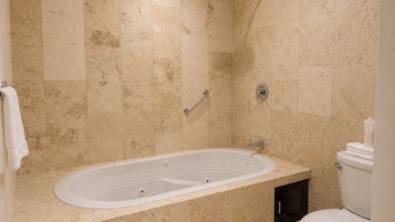 Un baño con una bañera independiente, un cabezal de ducha, un inodoro y un perchero para toallas.