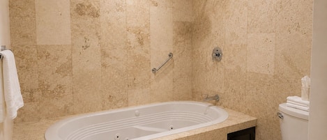 Un baño con una bañera independiente, un cabezal de ducha, un inodoro y un perchero para toallas.