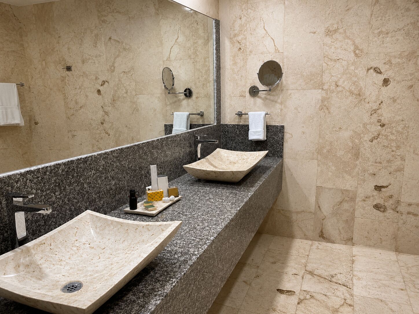 A bathroom with a large mirror, two sinks, and a shower area.