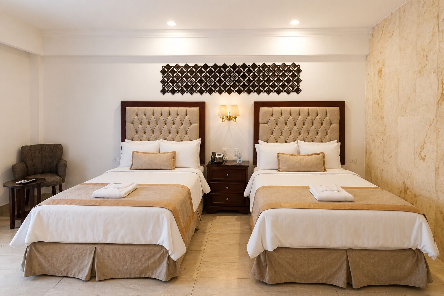 Een hotelkamer met twee bedden, een stoel, een nachtkastje en een decoratief wandobject.