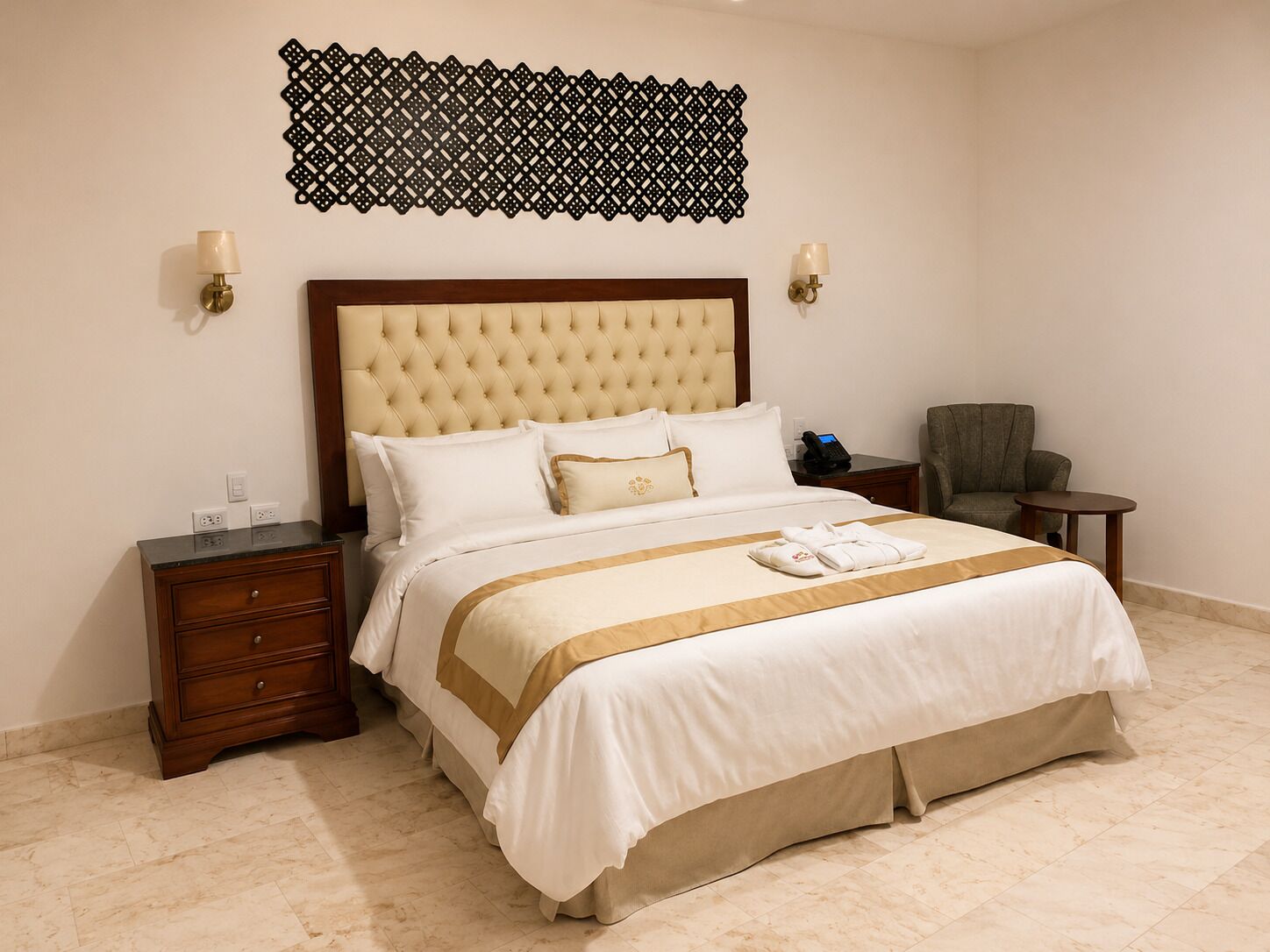 Une chambre d’hôtel avec un grand lit, une table de chevet en bois, une chaise, une petite table et un élément décoratif mural.