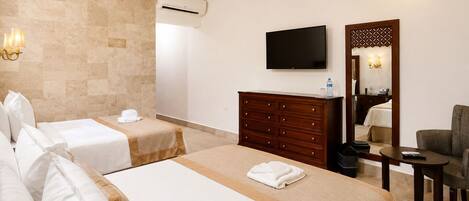 A hotel room with two beds, a TV, a dresser, a chair, and a mirror.