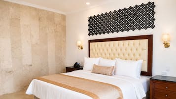 Una camera d'albergo con un letto grande, una testiera, lampade sui comodini, un tavolino e un pannello decorativo a parete.
