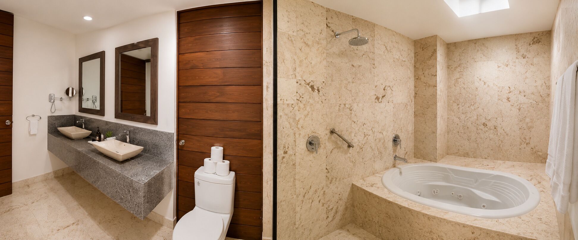 A bathroom with a vanity, two sinks, a toilet, a shower with a bathtub, and a wooden panel wall.