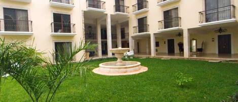 A courtyard with a central fountain, surrounded by a multi-story building with balconies.