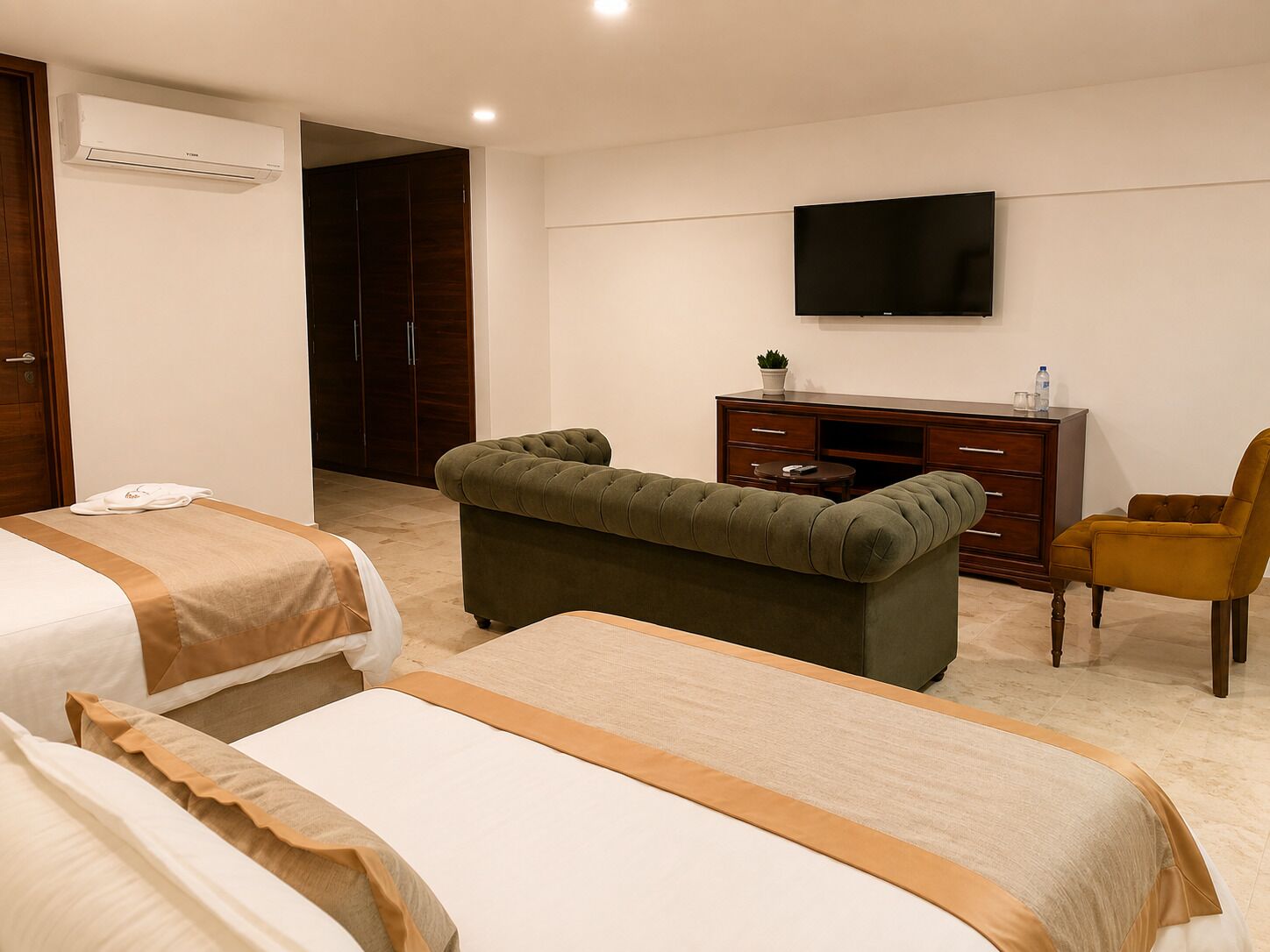 A hotel room with two beds, a television, a desk, and a chair.