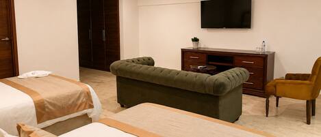 A hotel room with two beds, a television, a desk, and a chair.