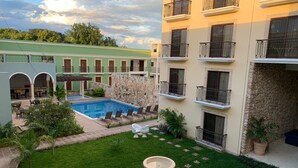 A courtyard with a swimming pool, a fountain, and a building with balconies. - Real Hispano (Valladolid)