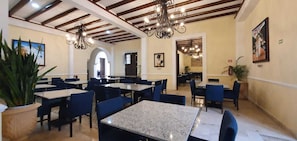 Un restaurante con varias mesas y sillas, candelabros y cuadros en las paredes.