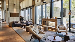 A spacious lounge area with a large window, a sofa set, and a fireplace. - Conrad Los Angeles (Los Angeles)