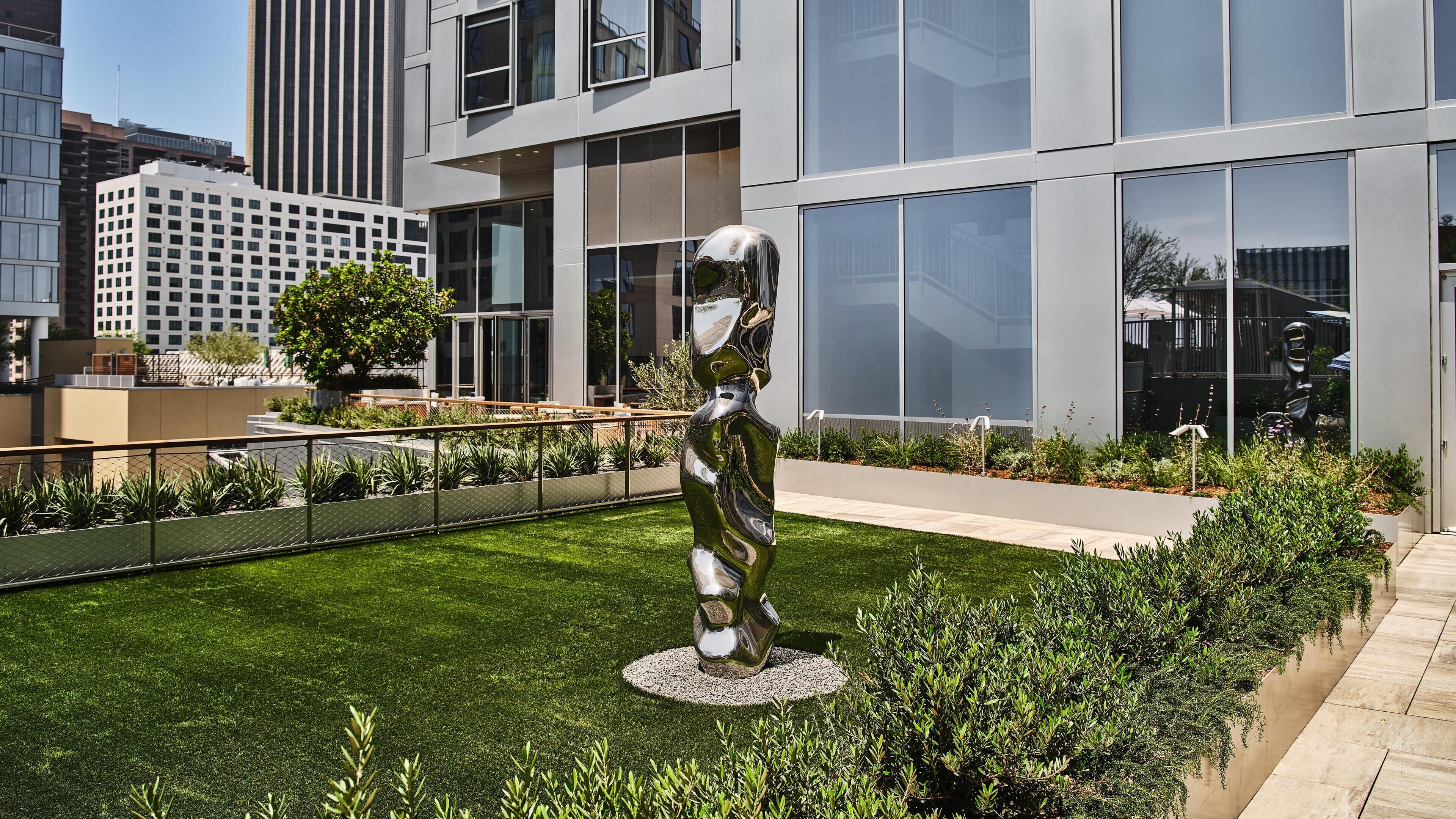 A modern building with large windows and a sculpture in the courtyard.