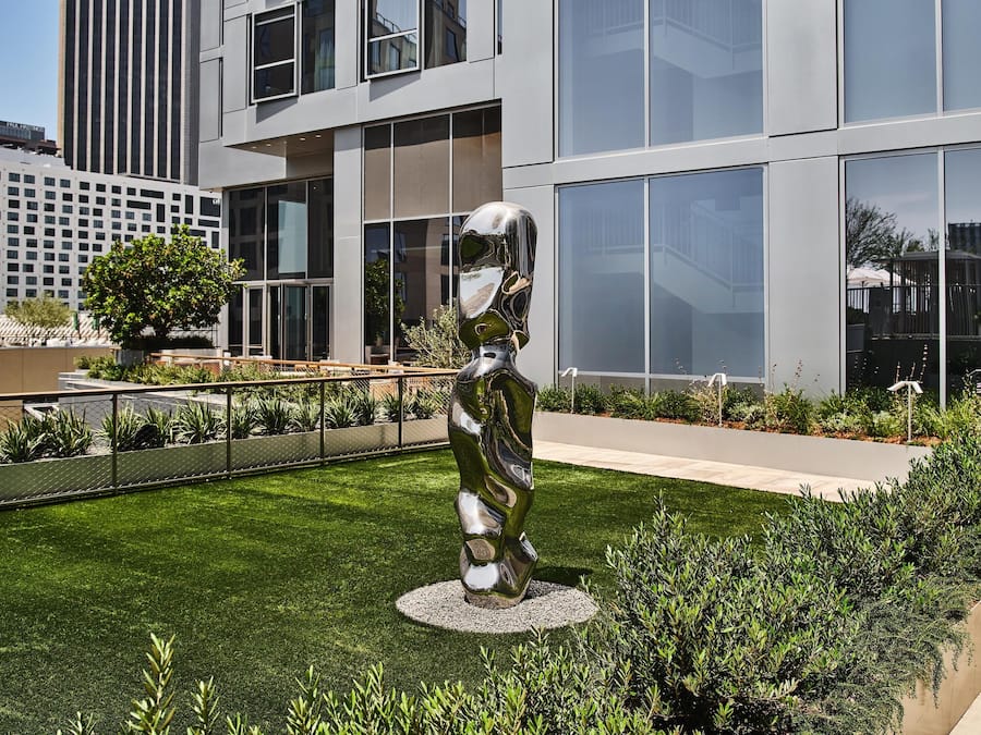 A modern building with large windows and a sculpture in the courtyard.