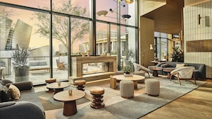 A modern interior with large windows, a fireplace, and a variety of seating arrangements. - Conrad Los Angeles (Los Angeles)