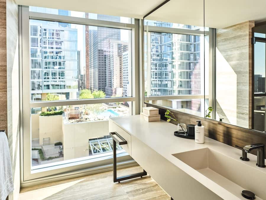 A modern bathroom with a large window, a sink, and a mirror.