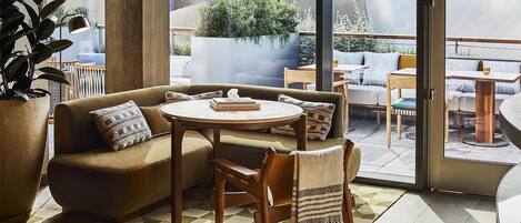 A modern interior with a large window, a sofa, a table, and a potted plant.
