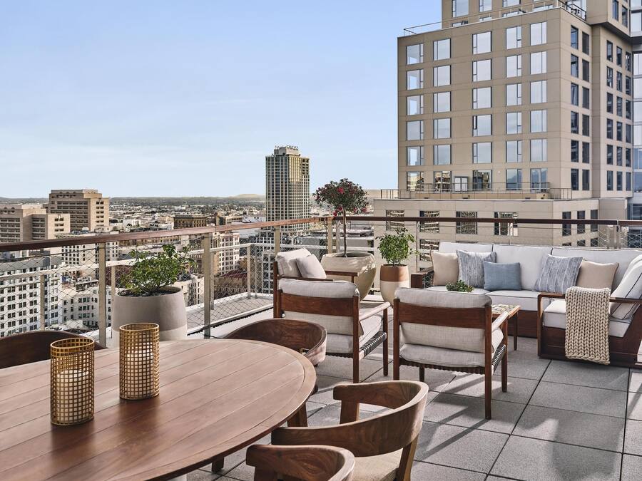 Eine Dachterrasse mit Holztisch, Stühlen und einer Sofagarnitur.