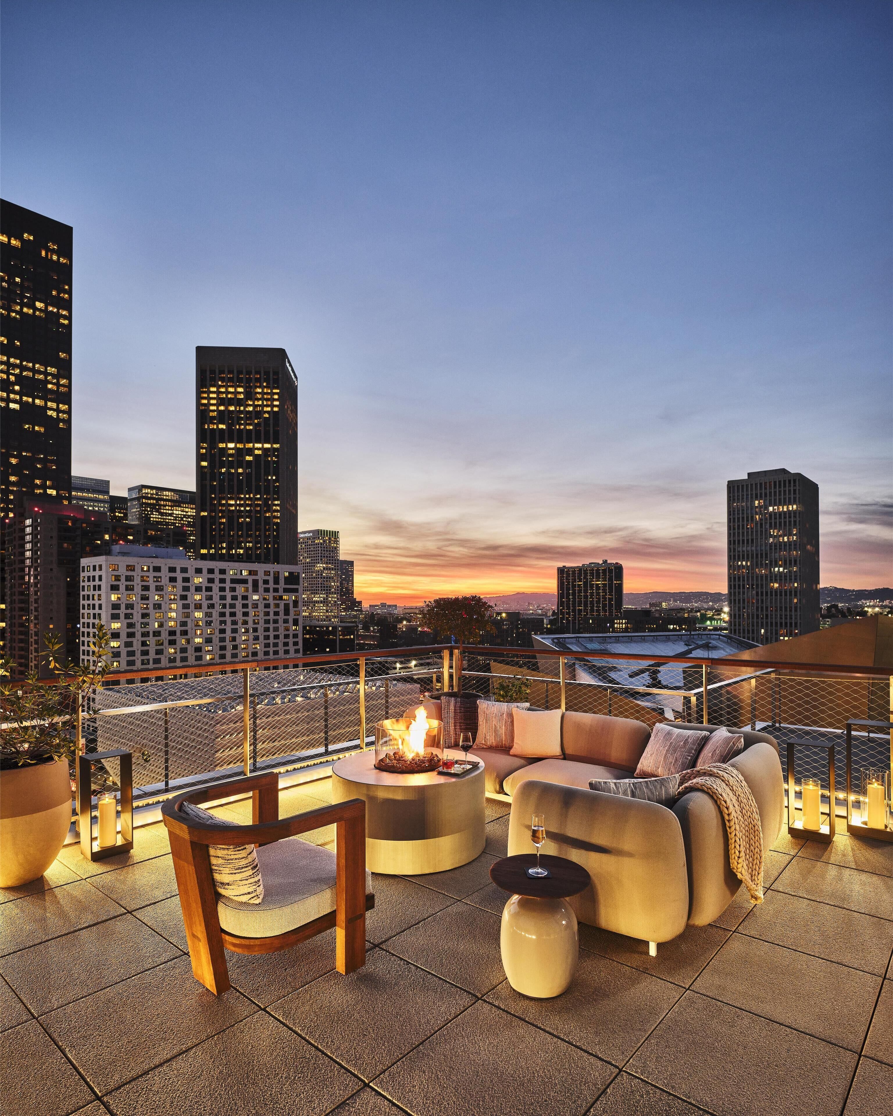 A rooftop terrace with a fire pit, seating area, and city skyline views.