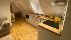 A compact kitchen with wooden flooring, a built-in oven, and a window above the sink.
