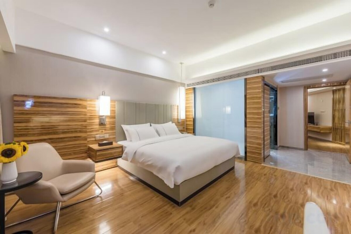 Une chambre d’hôtel moderne avec un grand lit, des tables de chevet, une chaise et une lampe.