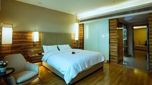 A modern hotel room with a large bed, a bedside table, a chair, and a small table with a lamp. - Borrman Hotel (Guilin)