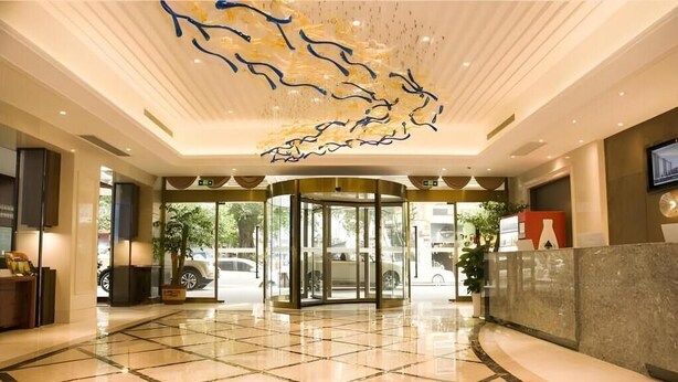 A hotel lobby with a revolving door, a reception desk, and a large abstract ceiling design. - Borrman Hotel (Guilin)