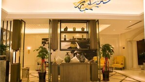 A lobby with a reception desk, potted plants, and a decorative wall with shelves. - Borrman Hotel (Guilin)