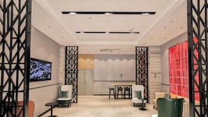 A modern hotel lobby with a seating area, a dining table, and a TV screen. - Borrman Hotel (Guilin)