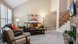 A spacious living room with a fireplace, a sofa set, a coffee table, and a painting on the wall.