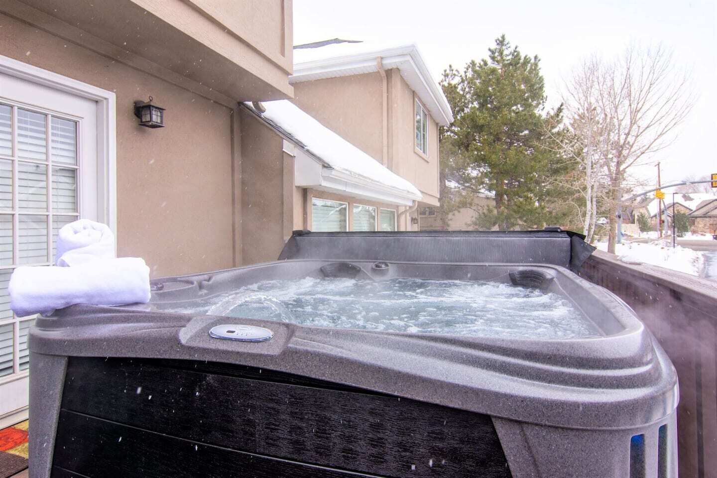 Ein Whirlpool mit Bedienfeld, Handtüchern und einem Haus im Hintergrund.