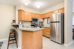 Enjoy cooking in this well-equipped kitchen with a granite countertop, microwave, stove, and sink.