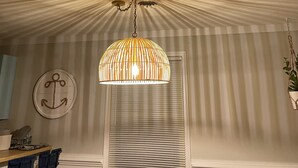 A room with a ceiling that has a radial pattern, a hanging lamp with a striped shade, a wall-mounted anchor decoration, and a window with blinds. - 4BR 3 Bath, Dog Friendly, Linens & Towels provided, 700ft to beach access (Kill Devil Hills)