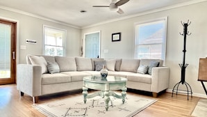 A living room with a beige sectional sofa, a glass coffee table, and a patterned rug. - 4BR 3 Bath, Dog Friendly, Linens & Towels provided, 700ft to beach access (Kill Devil Hills)