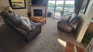 Ein Wohnzimmer mit Kamin, zwei Ledersofas, einem Couchtisch und einem Fernseher.