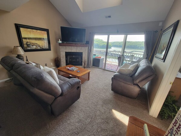 A living room with a fireplace, two leather sofas, a coffee table, and a TV.
