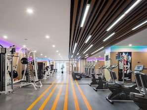 A gym with exercise equipment, a central aisle, and a mirrored wall. - Swissotel Shenyang (Shenyang)
