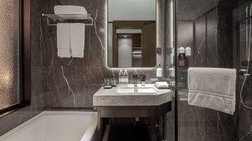 Un baño moderno con tocador de mármol, ducha con cerramiento de vidrio y un espejo grande.