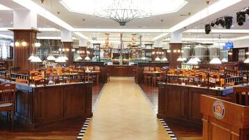A spacious restaurant with wooden booths and tables, a central bar area, and a modern chandelier.