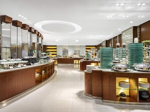 A modern hotel lobby with a curved reception desk, glass display cases, and a central seating area.