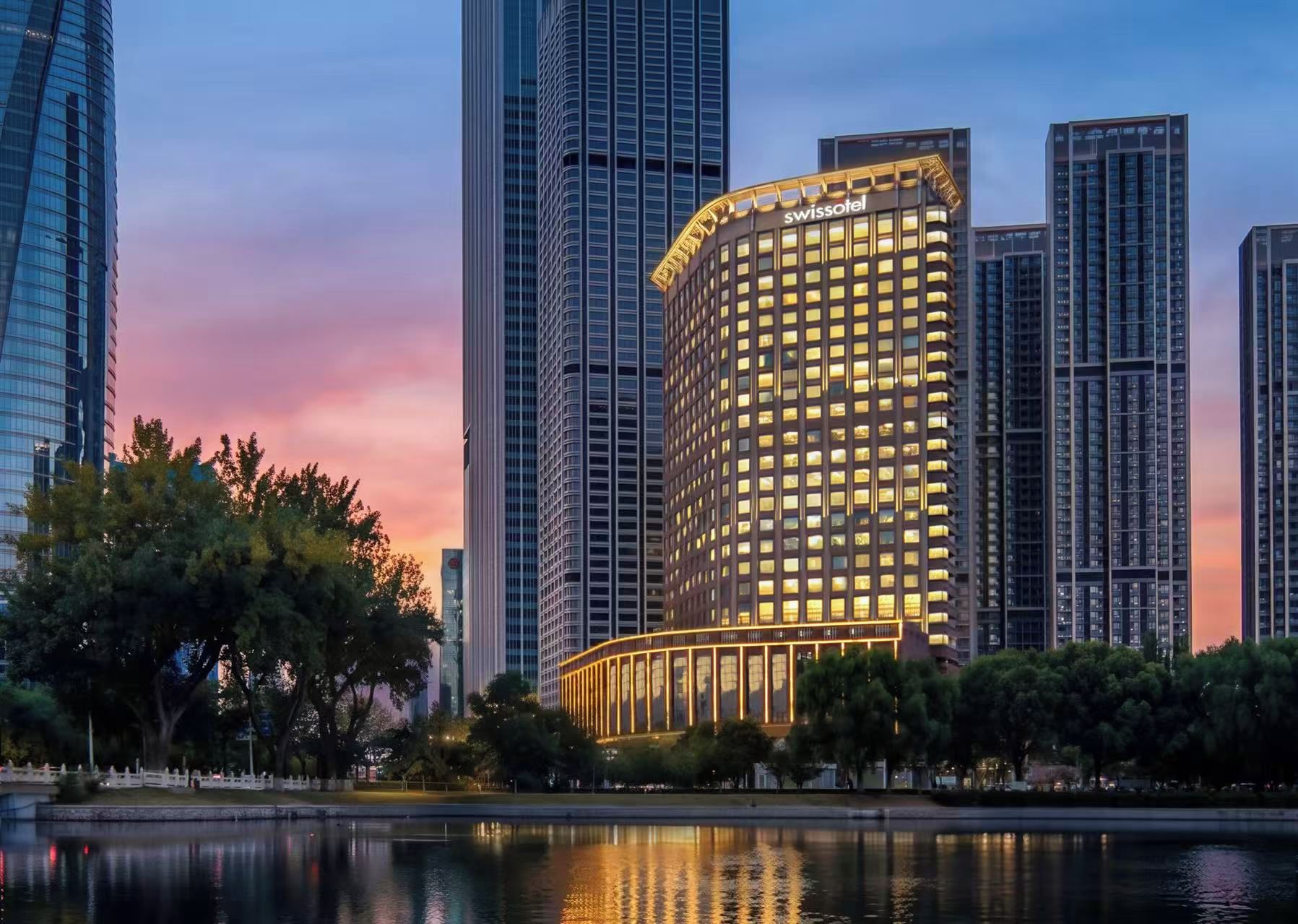 A high-rise hotel with a prominent 'swissotel' sign, surrounded by other tall buildings and a body of water.