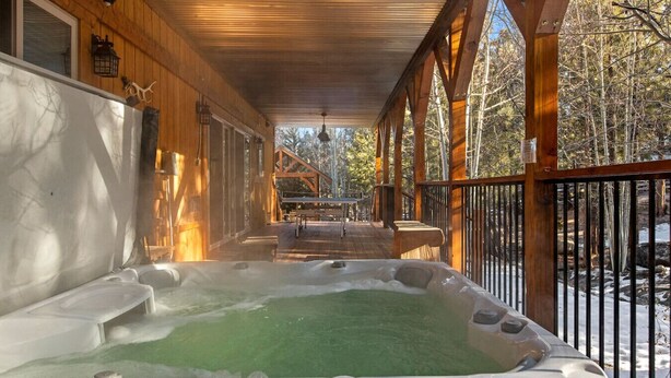 A hot tub on a wooden deck with a view of a cabin in the background. - Eagle Creek Lodge w/Spa (Big Bear Lake)