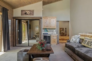 A spacious living area with a wooden table, a sofa, and a kitchen in the background.