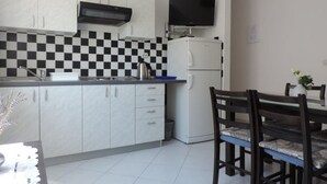 A compact kitchen with white cabinets, a black and white checkered backsplash, a white refrigerator, and a dining table with chairs. - Apartment in Duće with Seaview, Balcony, Air condition, WIFI (5067-2) (Duce)