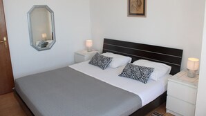 A neatly arranged bedroom with a large bed, two bedside tables, a mirror, and a framed artwork on the wall. - Apartment in Duće with Seaview, Balcony, Air condition, WIFI (5067-2) (Duce)