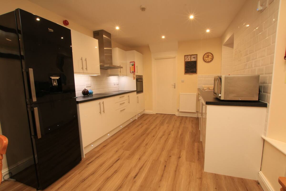 A modern kitchen with white cabinets, a black refrigerator, and a microwave.
