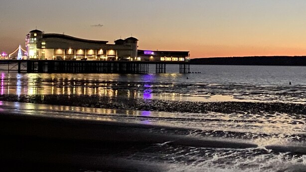 A waterfront building with a long pier extending into the water, featuring multiple levels and balconies. - The Kyrenia (Weston-super-Mare)